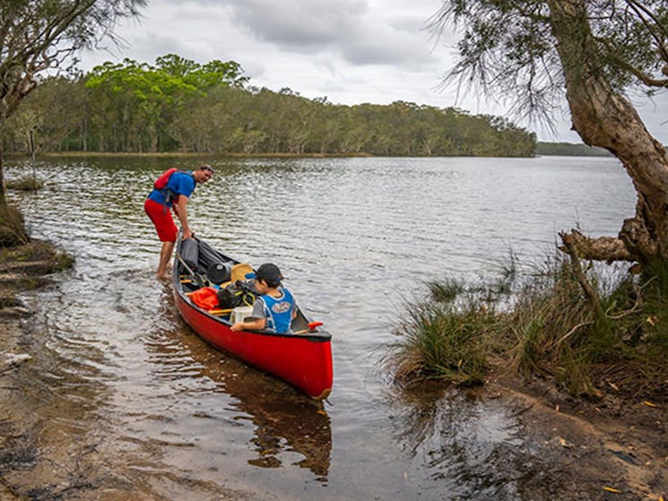 2 people in a canoe on Boolambayte Lake at Violet Hill campground in Myall Lakes National Park.
