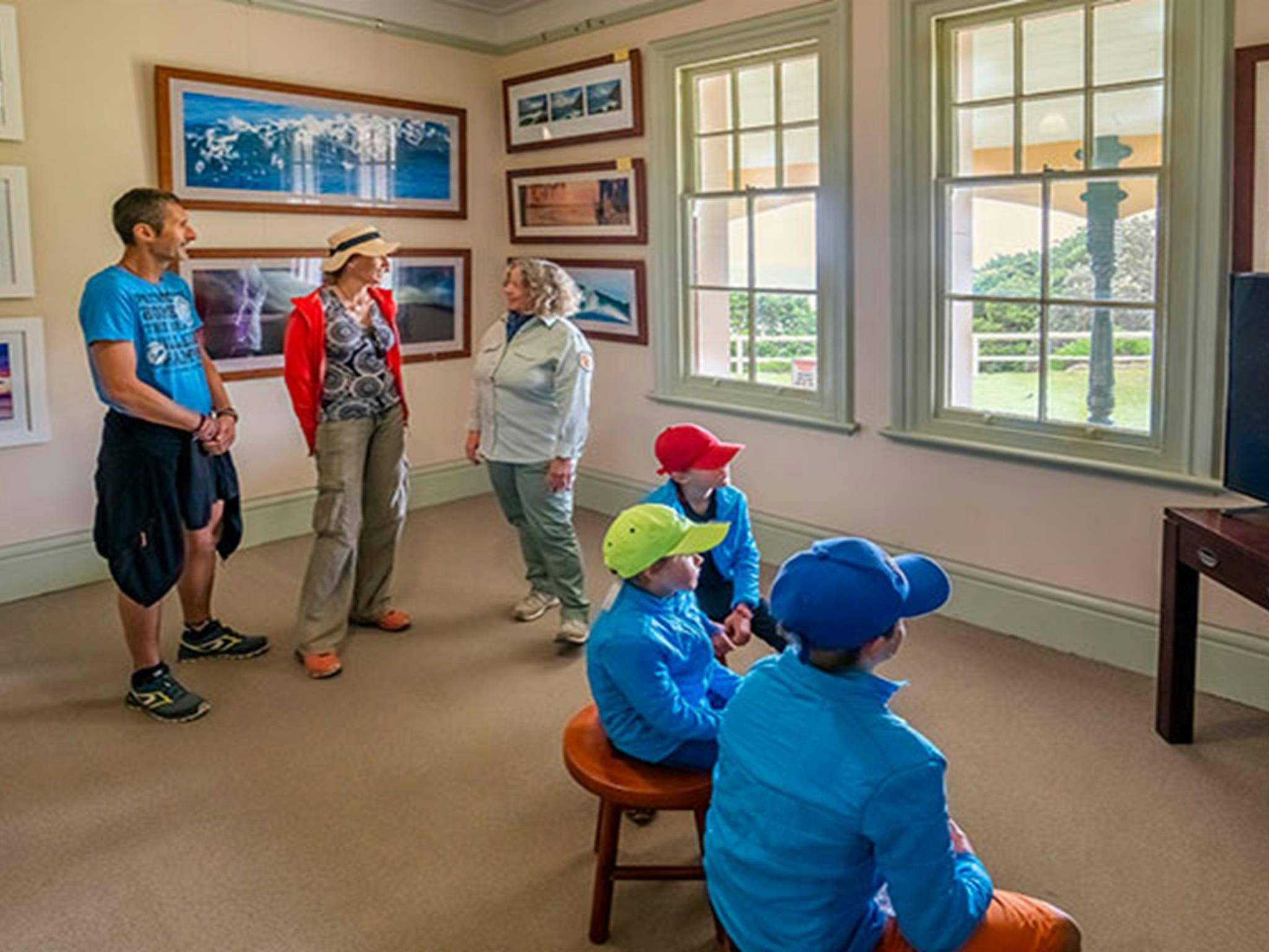 Visitors to Walgun Cape Byron Information Centre talking to an NPWS staff member in Walgun Cape