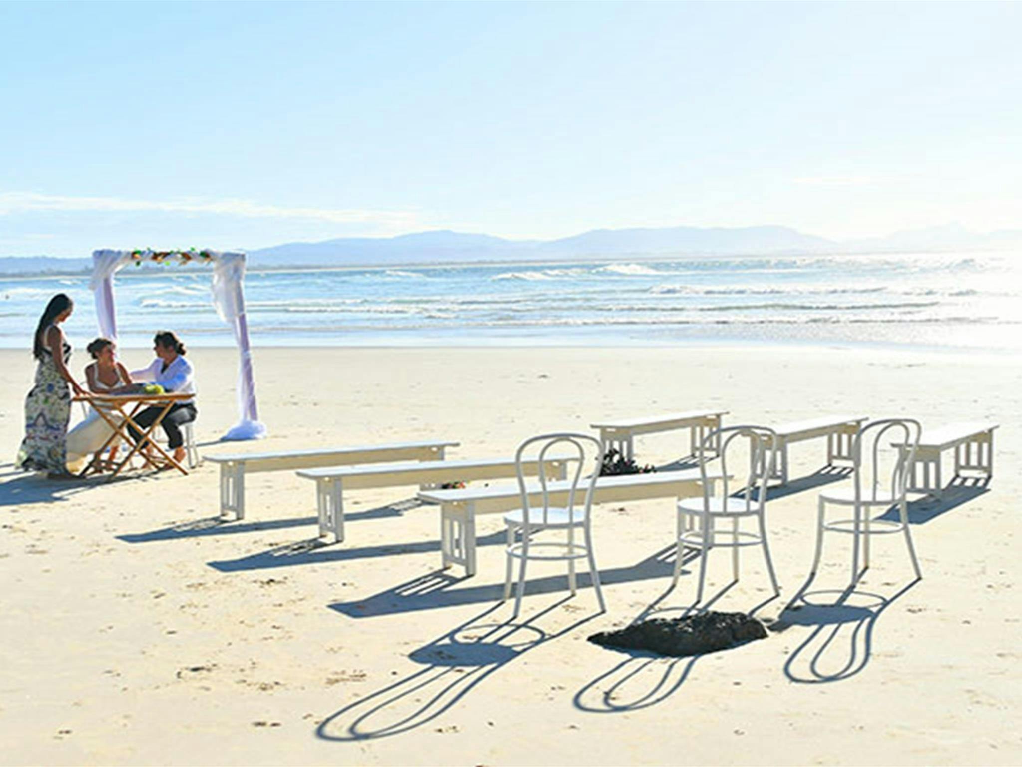 在沃特戈斯，一对新人和他们的证婚人在一张签字桌旁，前景中摆放着椅子和长凳。