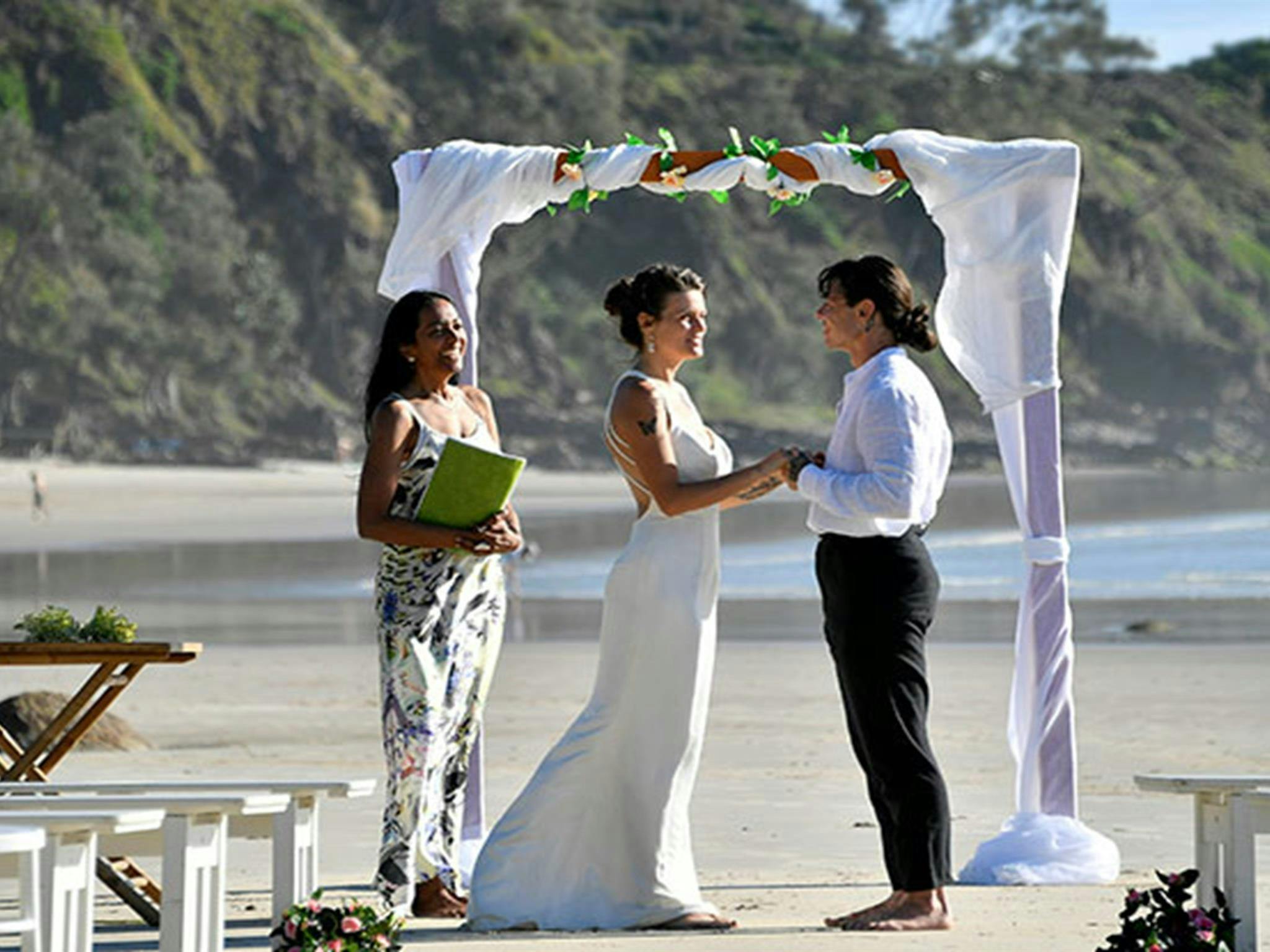 一对新人在拜伦角州立保护区沃特戈斯海滩的婚礼拱门下交换誓言