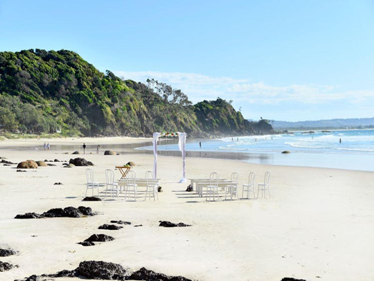 A wedding arch, benches and chairs set up for a wedding on Wategos Beach in Cape Byron State