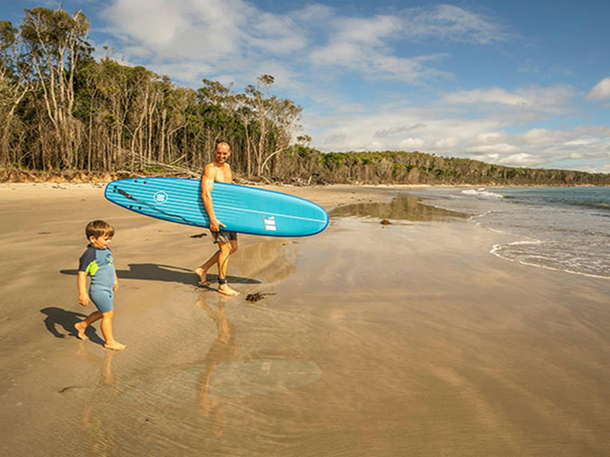 Ein Vater und sein kleiner Sohn paddeln auf dem Wasser, Campingplatz Woody Head, Bundjalung