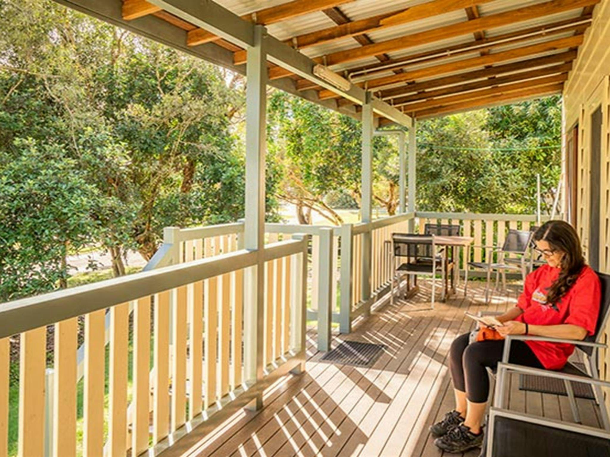 Cottage 6, woman reading on the verandah, Woody Head, Bundjalung National Park. Photo: John