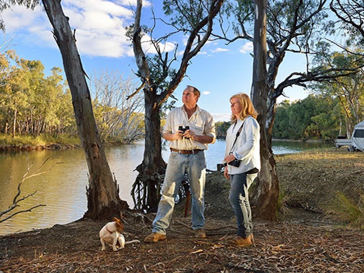 A couple and their dog next to the Murrumbidgee River with a tent in the background at Wooloondool