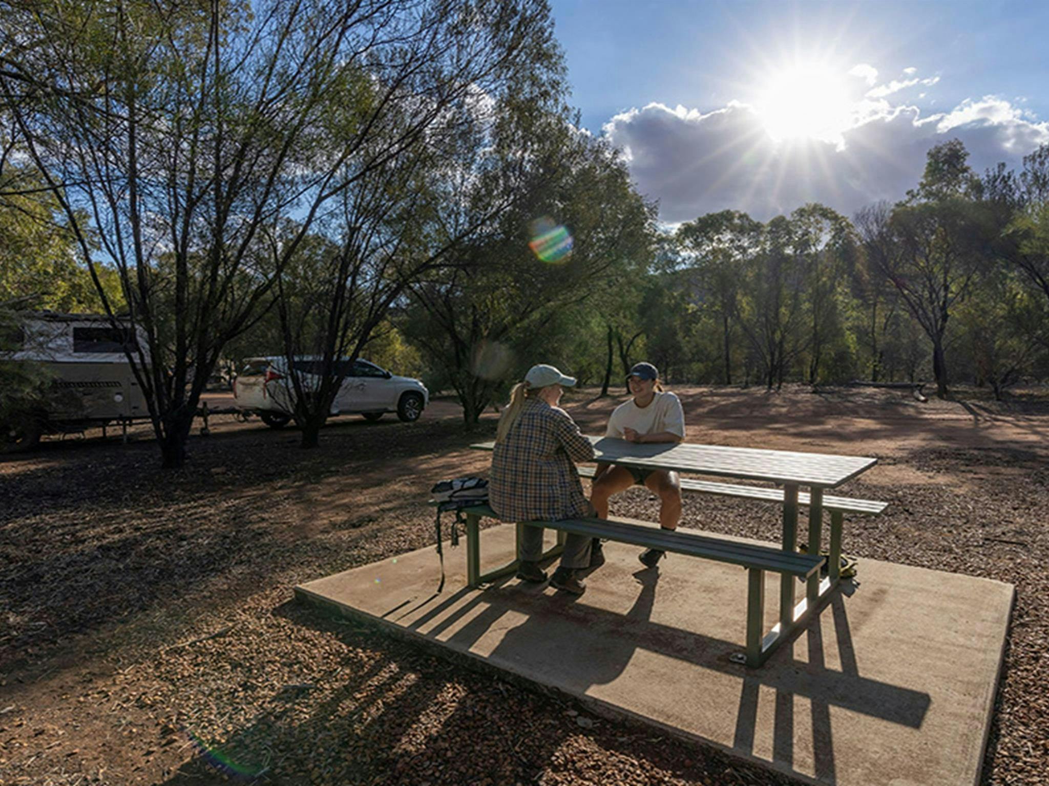 Two people sitting at the picnic table at Woolshed Flat campground in Cocoparra National Park.