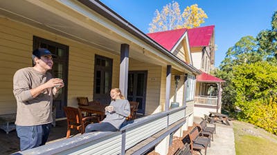 A couple on the verandah at Yarrangobilly Caves House 1901 section, Kosciuszko National Park. Photo: