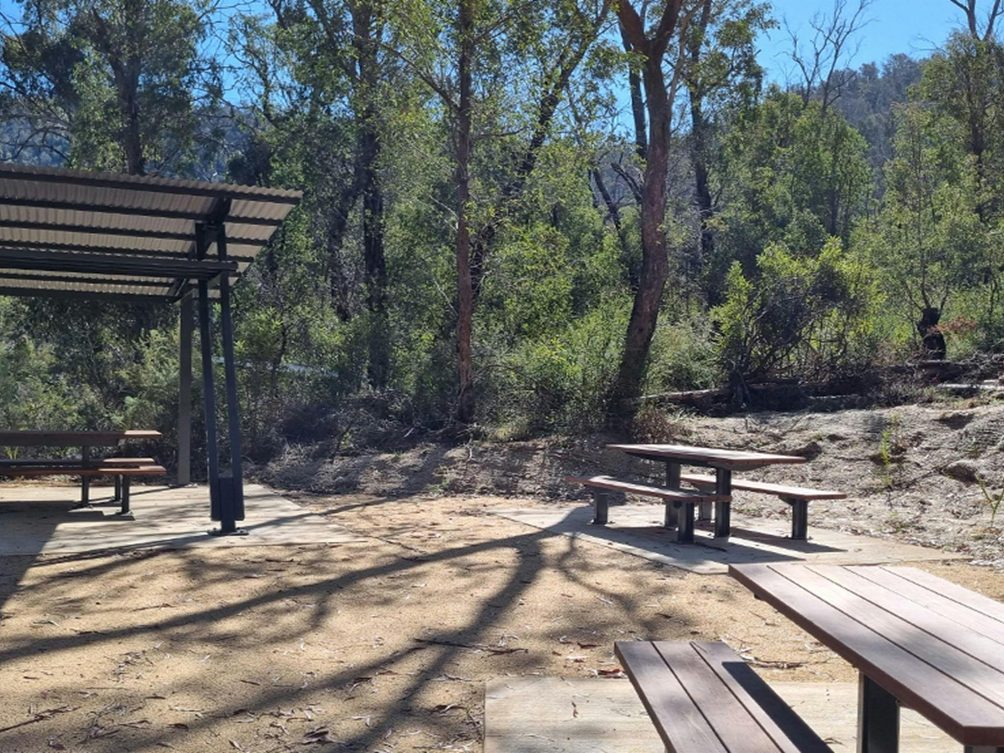 Offene und schattige Picknicktische im Picknickbereich rund um das Thermalbecken der Yarrangobilly Caves.