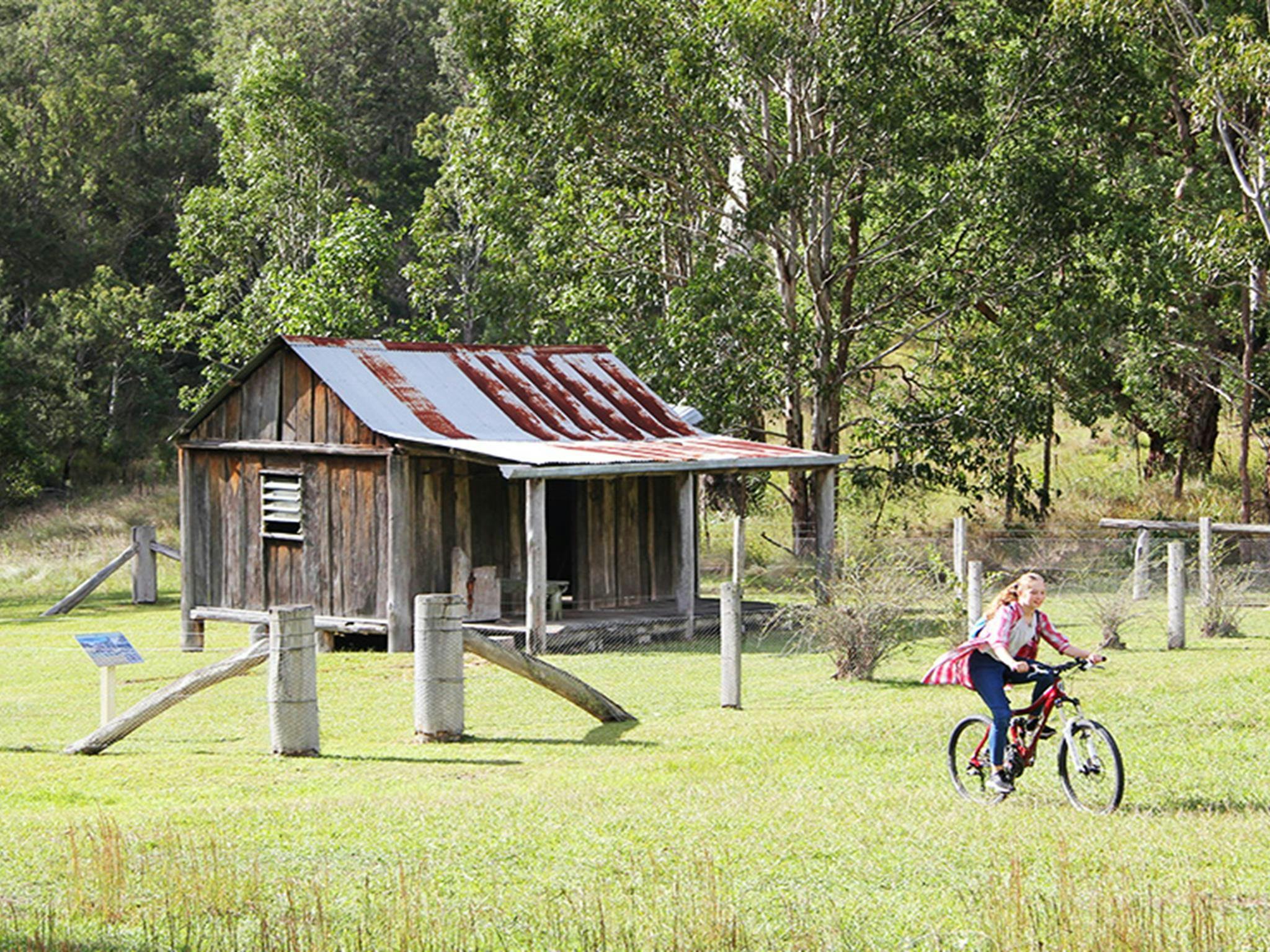 Girl rides a mountain bike in the campground paddock next to historic Youdales Hut. Credit: Natasha